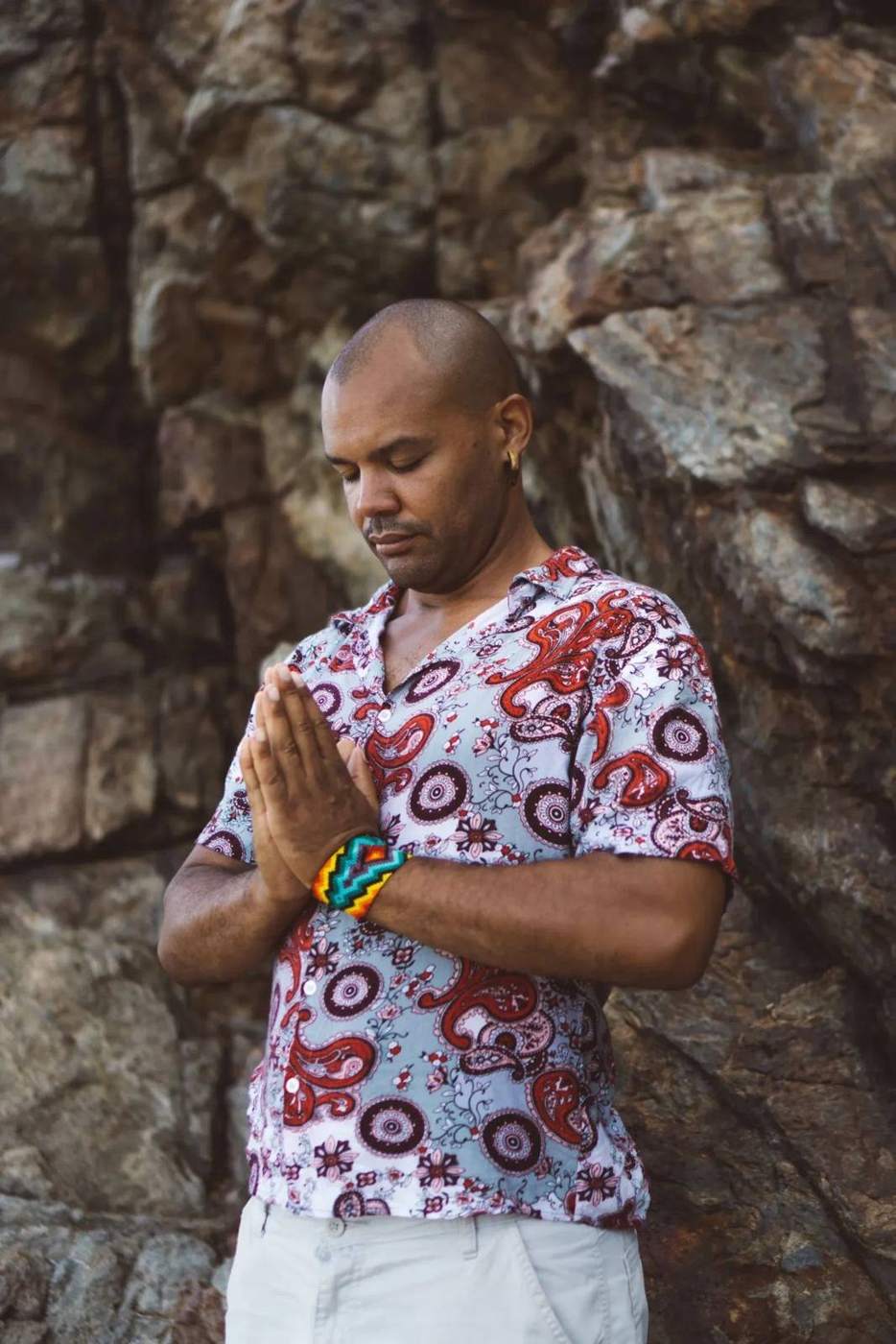 Andrew Kent in prayer pose against rock