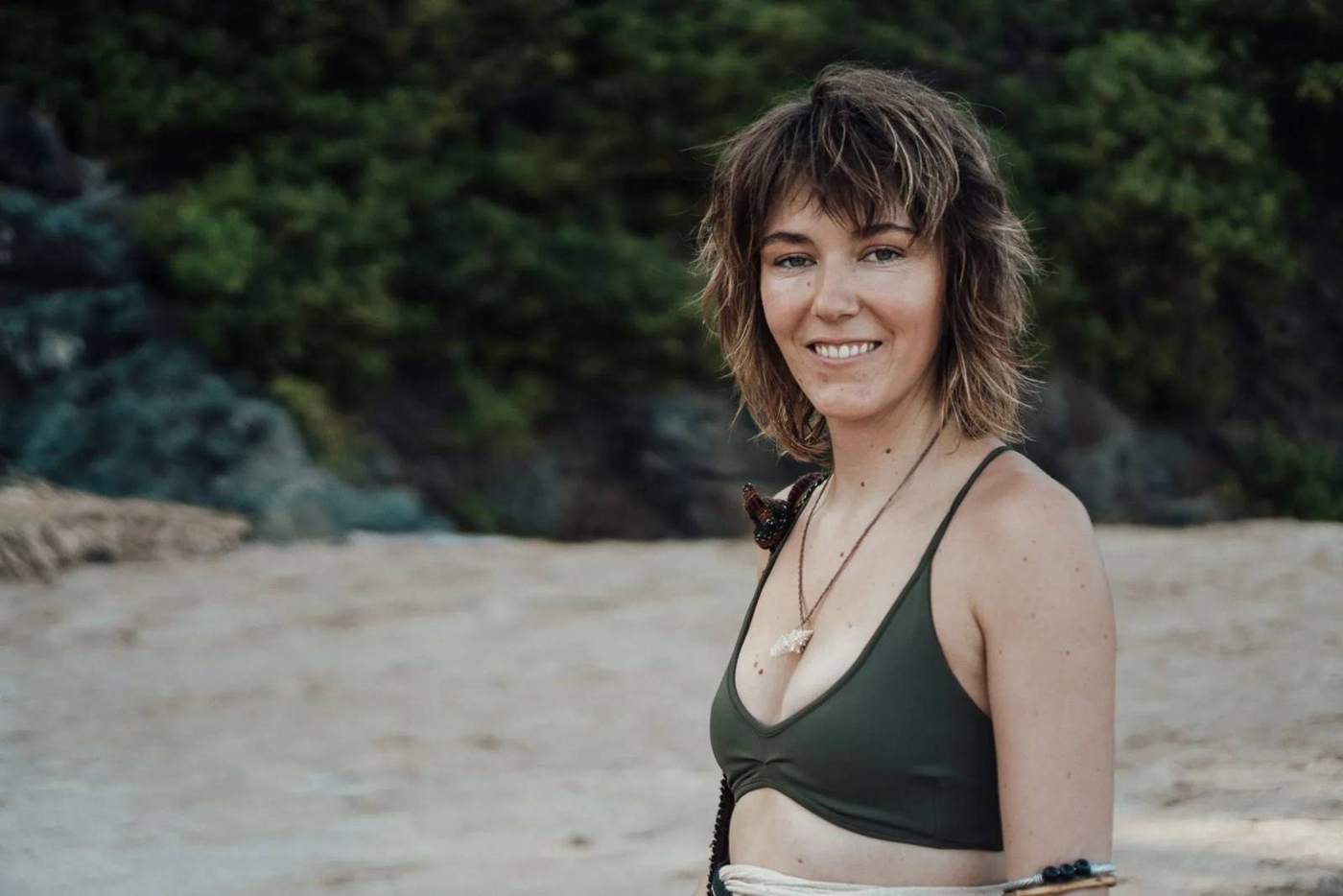 Imogen smiling on a sandy beach