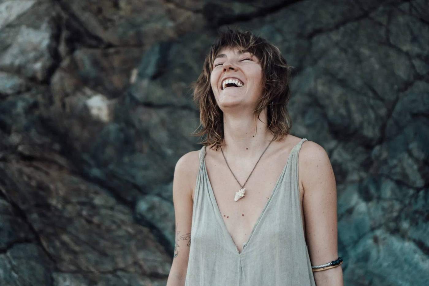 Imogen laughing on rocks by the sea