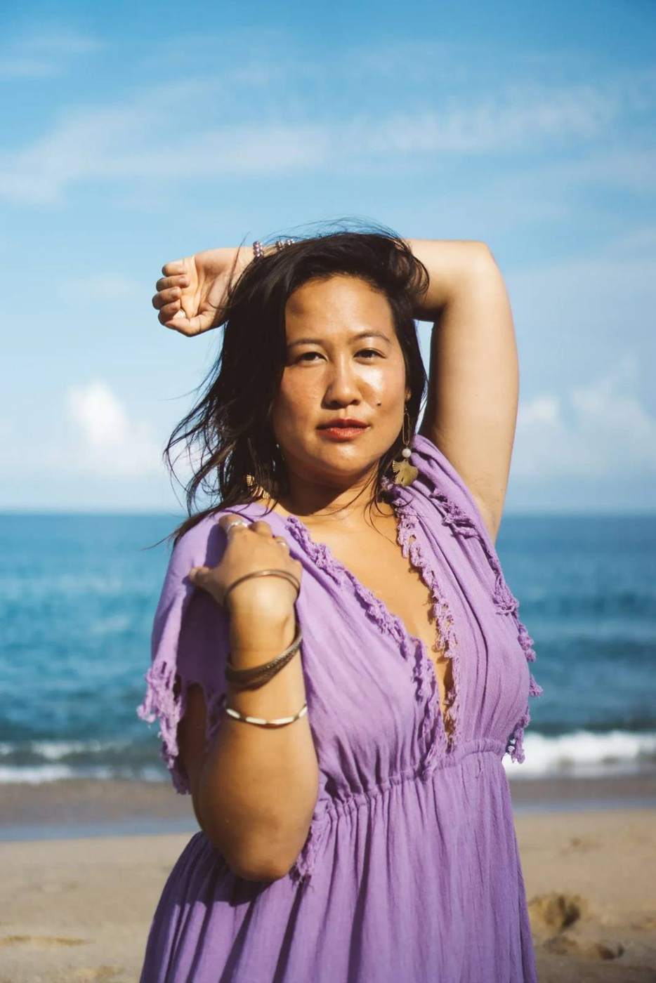 Lotus Wong with arm raised against the sea